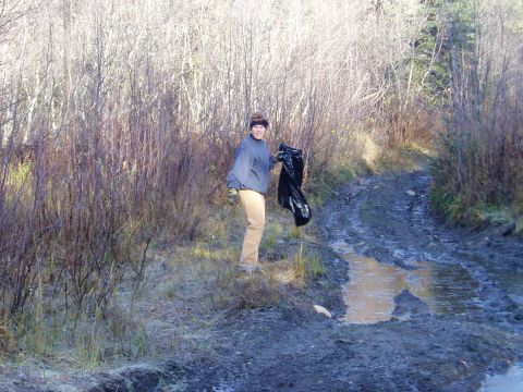 2000 Ford E350 - Person with trash bag on a muddy road surrounded by trees and brush.