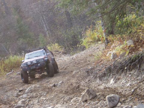 2000 Ford E350 - This modified SUV navigates a challenging, rocky trail through a wooded area.