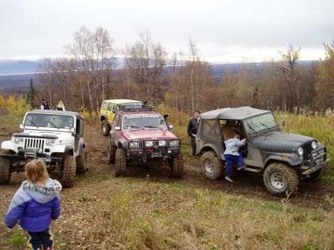 2000 Ford E350 - Several off-road vehicles are parked on a dirt path during an outing.