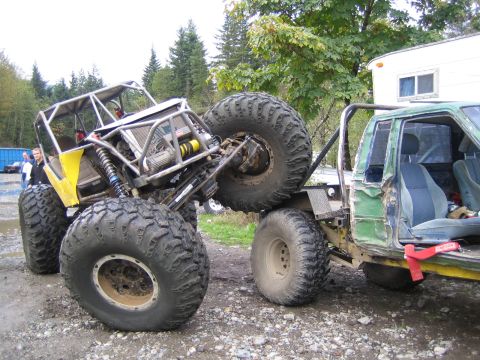 1990 Ford Bronco - Custom rock crawlers are shown interacting in an outdoor setting with trees and a trailer in the background.