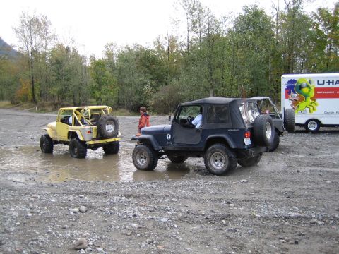 1990 Ford Bronco - Two Jeep Wranglers are parked in a muddy area, with a U-Haul truck visible behind them.