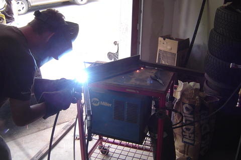 1987 Suzuki Samurai - A person is welding a metal frame with a Miller welding machine in a garage setting.