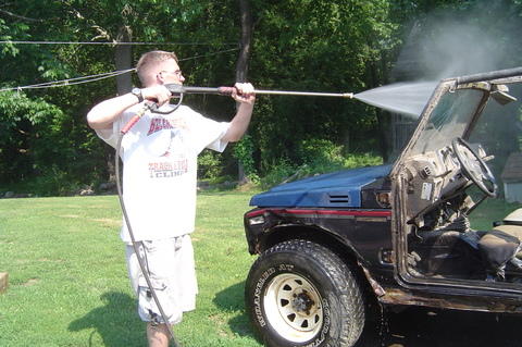 1987 Suzuki Samurai - A man pressure washes a 1987 Suzuki Samurai in a grassy yard.