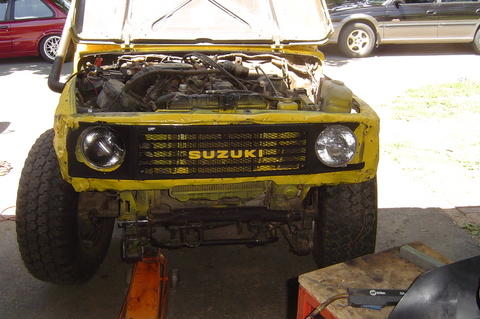1987 Suzuki Samurai - A yellow 1987 Suzuki Samurai is shown with its hood open and front end on a jack.