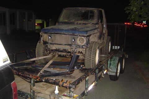 1987 Suzuki Samurai - A blue Suzuki Samurai is loaded onto a trailer at night, appearing to be in a state of disrepair.