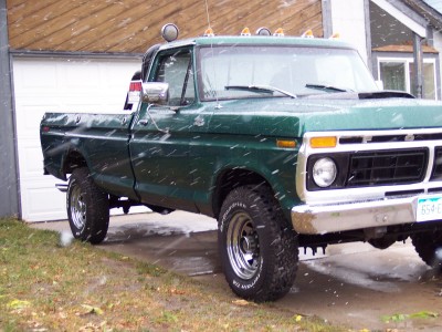 1972 Ford Ranchero - A green pickup truck is parked in front of a garage with snow falling.