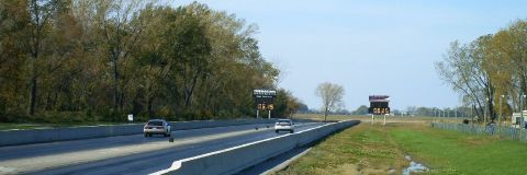 1992 Ford Probe - Two cars compete on a drag strip, with large digital timers displaying their race times.