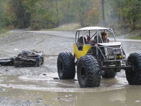 1990 Ford Bronco - Custom off-road buggy tows scrap metal through a wet, muddy area.