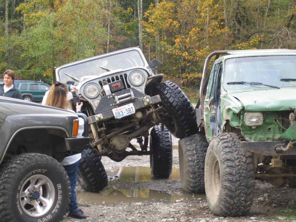 Jeep CJ-5 with winch and custom bumper, license plate 883-SBT, stuck between other off-road vehicles
