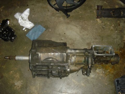 1991 Ford Crown Victoria - A transmission part is shown on a concrete floor, accompanied by cleaning supplies and other automotive components.