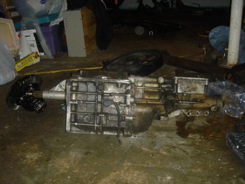 1991 Ford Crown Victoria - Transmission and differential assembly resting on a garage floor with various items in the background.