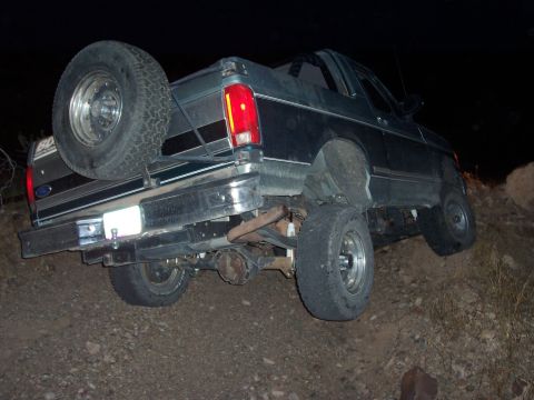 1996 Ford Bronco - Ford Bronco navigating rough terrain at night, showing its rear end and spare tire.