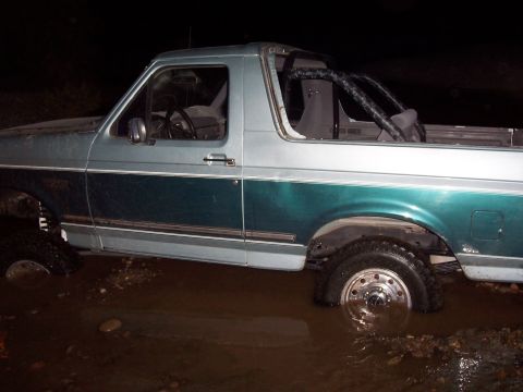 1996 Ford Bronco - This 1996 Ford Bronco is partially submerged in muddy water, with its tires deep in the mire.