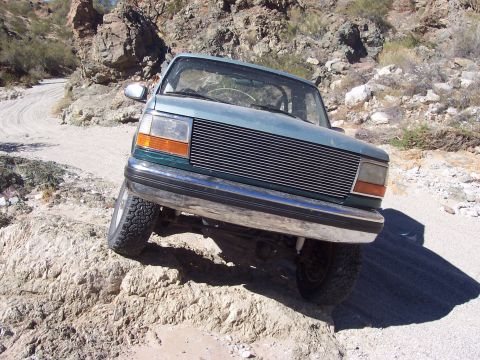 1996 Ford Bronco - This teal Ford Explorer is navigating a rough, rocky off-road path.