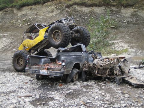 1990 Ford Bronco - A custom buggy is perched atop a severely damaged pickup truck in a rocky, outdoor setting.