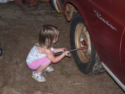1966 Ford Ranchero - A young child attempts to tighten the lug nuts on a 1966 Ford Ranchero, demonstrating an early interest in automotive maintenance.