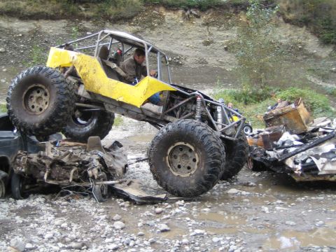 1990 Ford Bronco - Custom buggy navigates over destroyed vehicles in a challenging off-road environment.