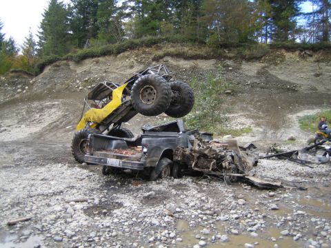 1990 Ford Bronco - Off-road buggy perched precariously on a severely damaged pickup truck in a rough terrain.