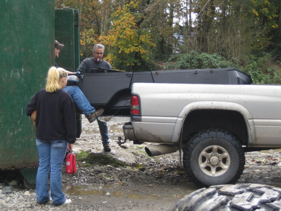 Silver pickup truck rear quarter panel and bed, side view. People loading items