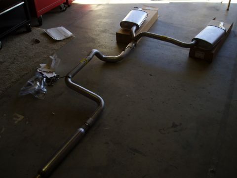 1993 Ford Taurus - A new exhaust system, likely for a car, is laid out on a garage floor.