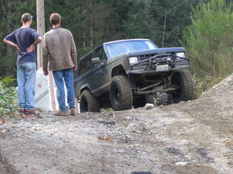 1990 Ford Bronco - Modified Ford Bronco navigates a steep, rocky incline with two onlookers observing.
