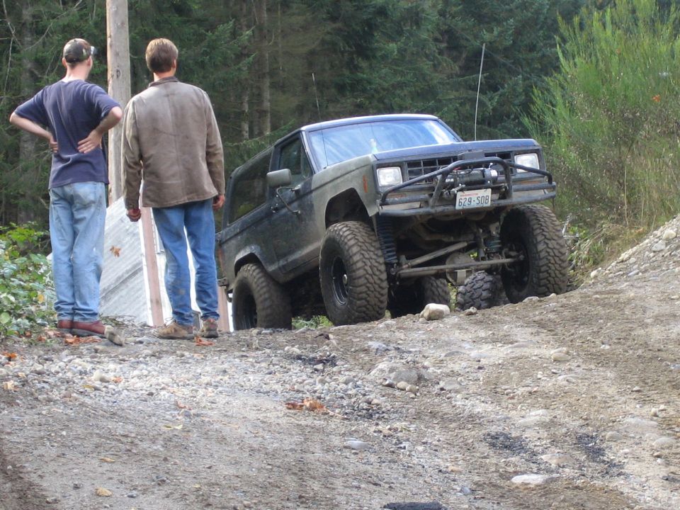 Olive green Ford Bronco with off-road tires and winch on a dirt trail