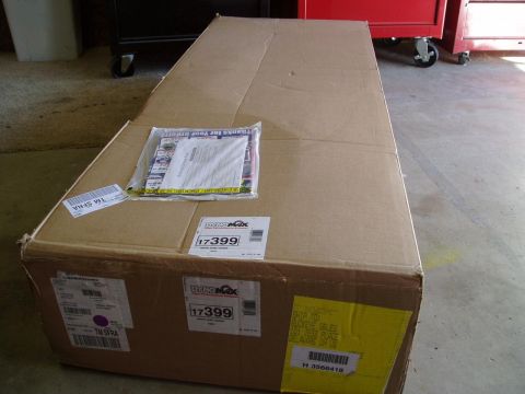1993 Ford Taurus - A large cardboard box, likely containing an exhaust part, is shown with various shipping labels and a catalog attached.