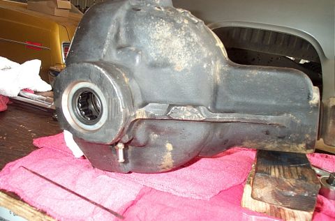 1995 Ford Bronco - Side view of a grimy cast-iron differential housing sitting on a pink shop towel and wood block on a workbench, with the pinion seal remove…