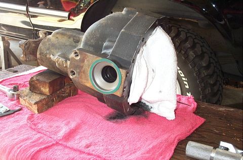 1995 Ford Bronco - A removed cast-iron differential center section rests on a red shop towel and wood blocks, ring-gear opening stuffed with a white rag and t…