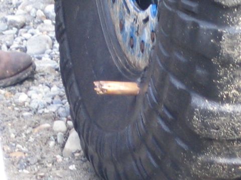 1990 Ford Bronco - A tire has a foreign object lodged in its tread, with a boot visible nearby.