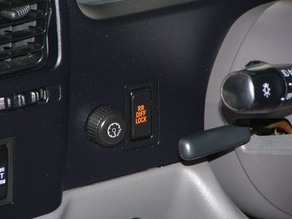 Dashboard close-up of a dimmer knob and orange RR DIFF LOCK switch beside the turn-signal stalk