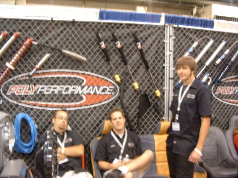 2004 Toyota Tacoma - Three men stand and sit in front of a PolyPerformance display various shock absorbers and suspension parts.