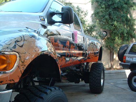 2004 Toyota Tacoma - Custom graphics adorn a lifted pickup truck, with another vehicle partially visible.