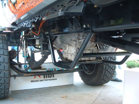 2004 Toyota Tacoma - The underside of a modified truck is visible, heavy-duty suspension and large tires.