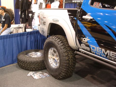 2004 Toyota Tacoma - This customized truck features aggressive off-road tires and striking blue and black graphics on its side panel.