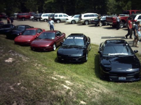 1995 Ford Probe - Several Ford Probes are parked in a lot, with some people walking in the background.