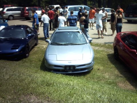 1995 Ford Probe - Three cars are parked on grass with a group of people standing around them.