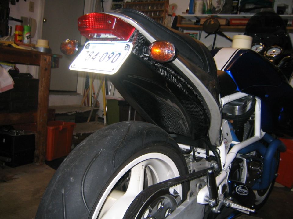 Motorcycle rear with license plate 784-090, black seat cowl with carbon fiber accents, and white wheel