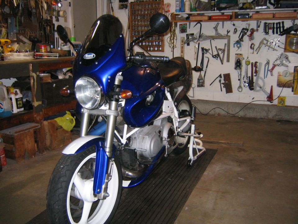 Blue and white Buell motorcycle parked in a tool-filled garage, front three-quarter view