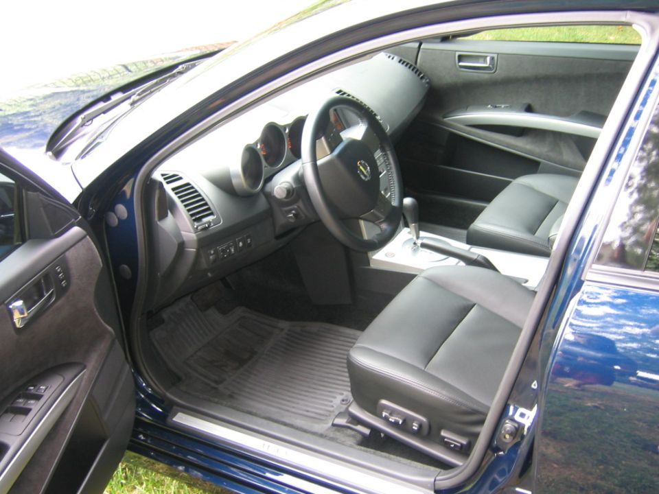 Black leather interior of a blue Nissan sedan, driver side