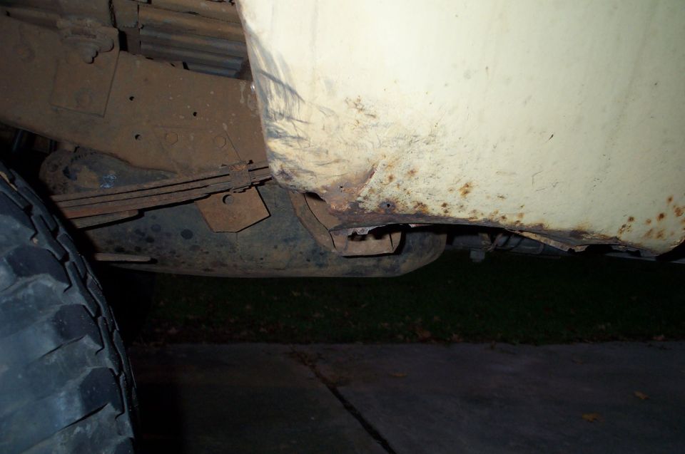 Truck's rusty rear quarter panel and leaf spring suspension