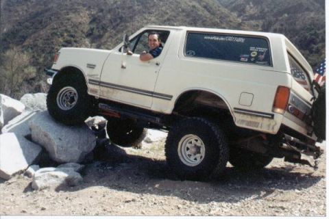 1990 Ford Bronco - This lifted Ford Bronco is navigating a rocky obstacle course with an American flag on the spare tire carrier.