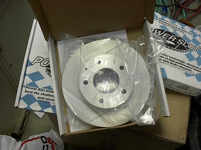New Power Slot brake rotor in plastic wrap, inside its box with documentation