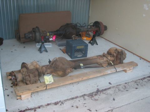 1991 Ford Bronco - Two vehicle axles, likely Dana 60 front axles, are shown resting on wooden pallets in what appears to be a storage unit.