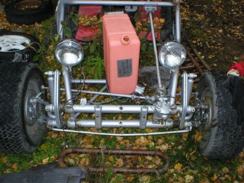 2003 Jeep TJ - The front end of a custom-built buggy sits outdoors with fallen leaves on the ground.
