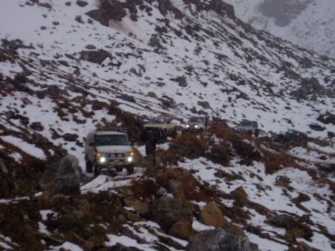 2000 Ford E350 - Several SUVs navigate a treacherous, snowy mountain trail during snowfall.