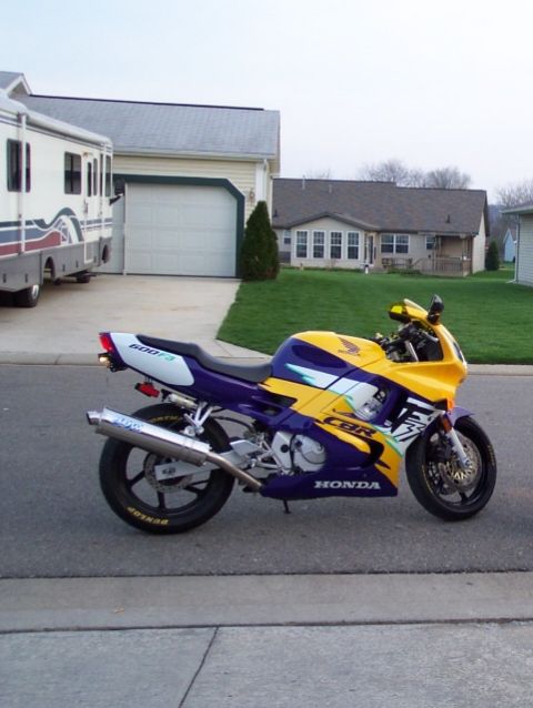 2003 Suzuki LTZ400 - A Honda CBR motorcycle is parked on the street in front of a residential house and RV.