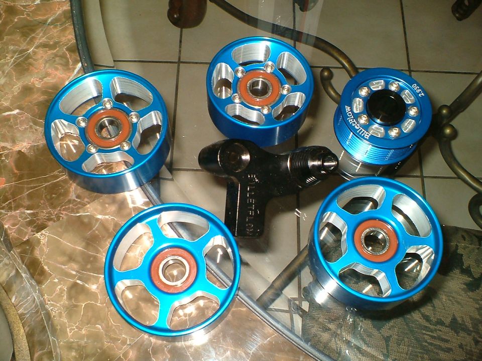 Blue anodized BilletFlow pulleys and a 2.930 supercharger pulley with black removal tool on a glass table