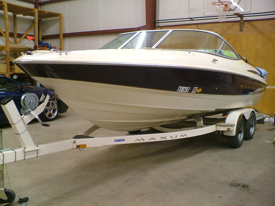 Cream and maroon Maxum bowrider boat on white tandem-axle trailer indoors