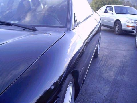 1994 Ford Probe - A dark coupe is parked next to another vehicle on an asphalt surface.